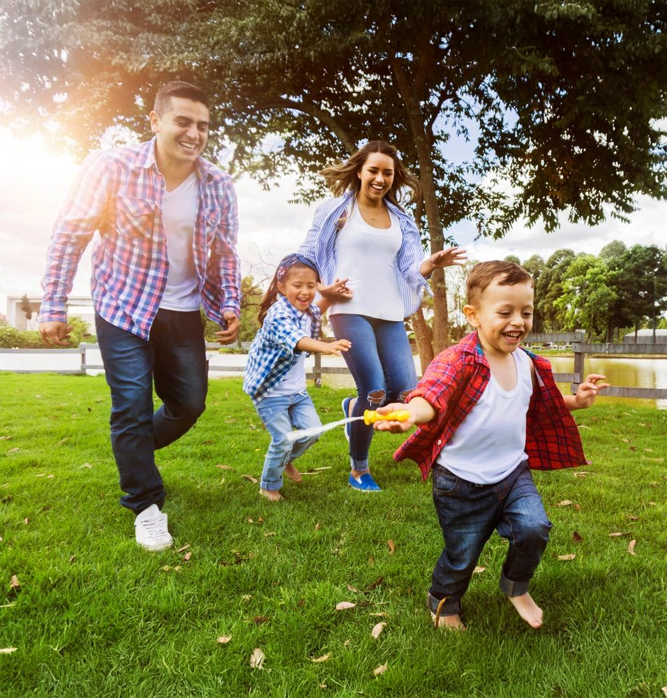 Family running through grass by Greener Grass Company